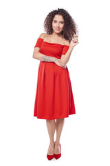 Beautiful curly female in red dress and red high heels shoes in full length looking at camera touching her hair