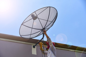 Technician installing Satellite dish system for television signal.