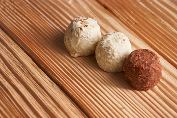 Macro. White and milk chocolate candies on a light wooden background