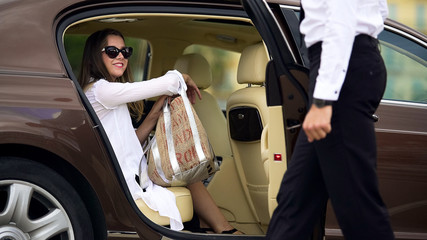Luxury taxi service, chauffeur opening car door for female passenger, travel