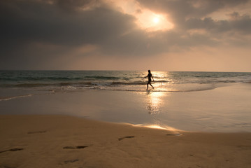 Fototapeta na wymiar Woman is wallking on Hikkaduwa beach, Sri Lanka
