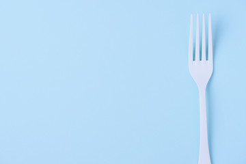 White fork on trendy soft blue paper background with side copy space