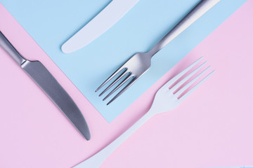 Knife and fork creative flat lay on soft pink and blue trendy pastel background