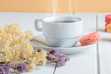 Different types color of macaroons with Cup of hot tea on white wooden background