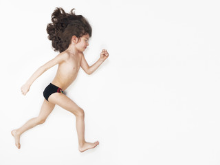 Young Caucasian boy running action on light background