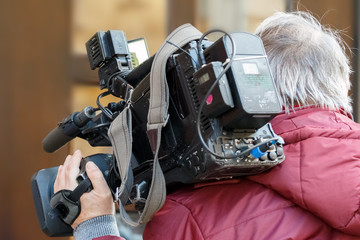 cameraman holding his professional camcorder in the street