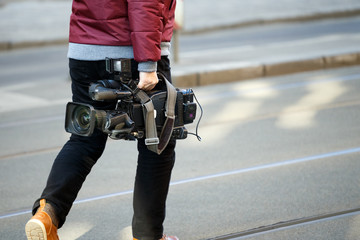cameraman holding his professional camcorder in the street