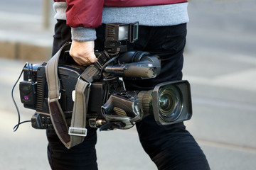 Obraz premium cameraman holding his professional camcorder in the street. Operator in social environment, filming, news outlet, motion-picture cameraman