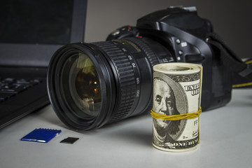 A lot of dollars near the camera and laptop