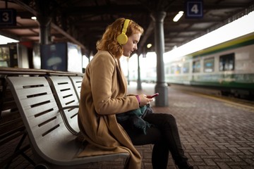 Beautiful young woman listing music while using her mobile phone