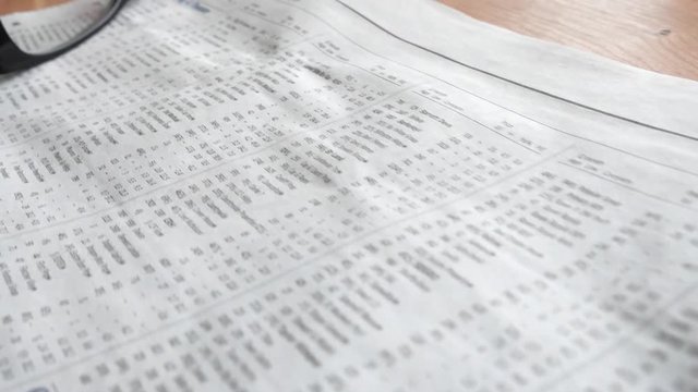Camera move over the equity prices page in the business section of a newspaper.