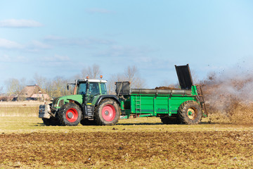 Obraz premium Tractor with manure spreader on the field - 1303