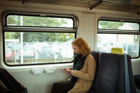 Red hair young woman using smartphone in train