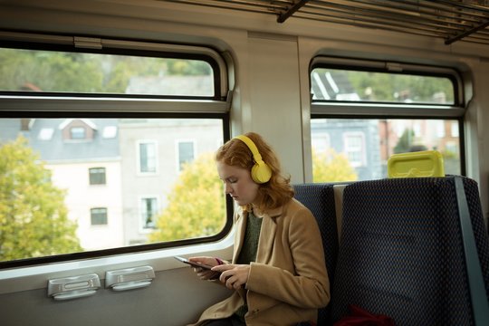 Young woman listing to music while using tablet
