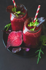 Fresh beetroot smoothie, beet, arugula and lettuce leaves on dark wooden background