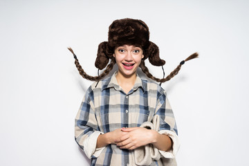 happy Russian girl in fur hat with pigtails smiling, holding felt boots