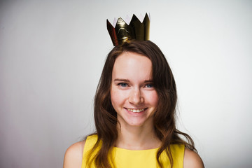 happy young girl in a yellow dress smiles, on her head a golden crown
