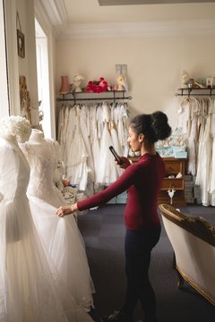 Woman Taking Photo Of Wedding Dress Mobile Phone In The Boutique