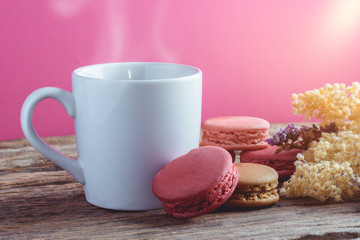Different types color of macaroons with Cup of hot tea on Old grunge wooden background