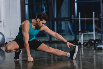 Obraz na płótnie Canvas sportsman stretching legs in sports center