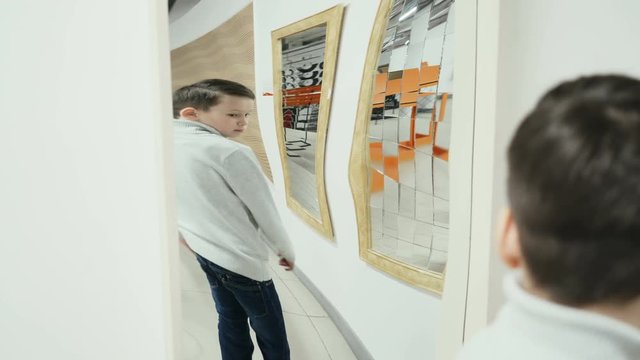 Boy playing with distorted mirror