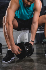 Fototapeta na wymiar muscular sportsman exercising with dumbbell in sports center