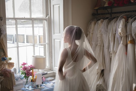 Bride in wedding dress looking through window