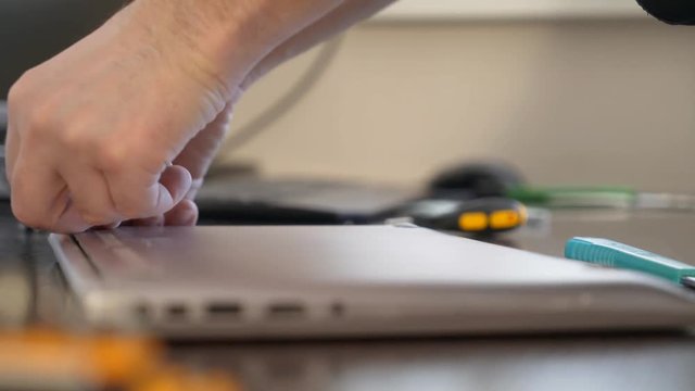 The wizard uses a screwdriver to twist the screw on the lid of the notebook.