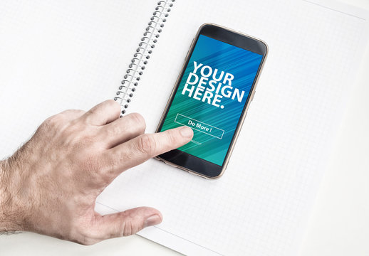 User with Smartphone on Graph Paper Notebook Mockup