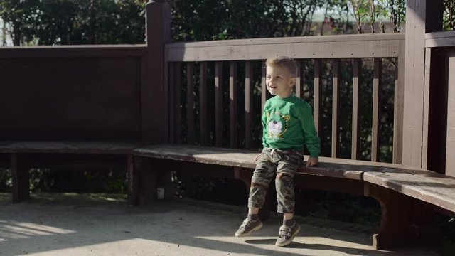 Little Cute Boy Sitting on a Bench in the Park 4k