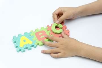 children's hands hold abc puzzle