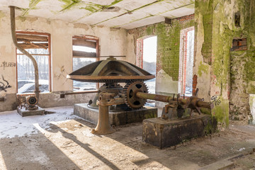 Abandoned water mill. Rusty wheels and green moss covered the old brick wall, natural background