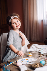 Happy easter! Cute little child girl painting with blue and yellow colors Easter eggs. family preparing for Easter