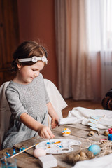Happy easter! Cute little child girl painting with blue and yellow colors Easter eggs. family preparing for Easter