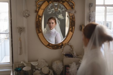 Reflection of young bride in a wedding dress in the mirror