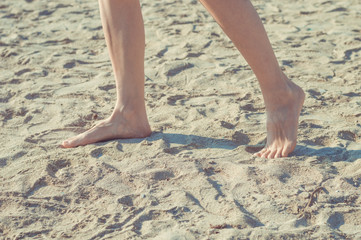 Fototapeta na wymiar Close up of woman legs walking barefoot on sand in summer holidays on the beach. Vacation concept.