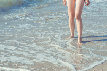 Close up of woman legs walking barefoot on beach in summer holidays. Vacation concept.