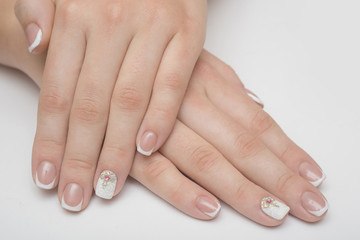 Naklejka premium Manicure with rhinestones in the shape of hearts and pink balls on white and red nail Polish on a white background.