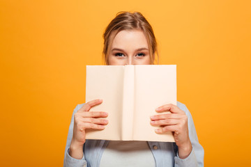 Happy young lady student covering face with book
