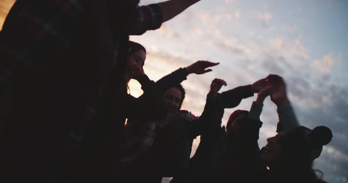 Hipster friends doing high five on a beach at sunset