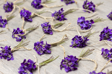 Obraz na płótnie Canvas small bouquets of fragrant forest flowers violets on old wooden background