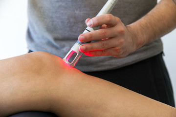 Laser therapy on a knee used to treat pain. selective focus - obrazy, fototapety, plakaty