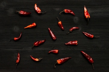 Heap of dry red chili pepper on black kitchen table surface background. Spicy food.