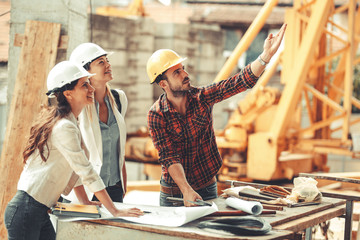 Two female inspectors and architects discuss with head engineer about construction project.People at work concept. - obrazy, fototapety, plakaty