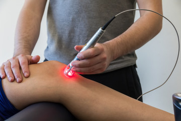 Obraz na płótnie Canvas Laser therapy on a knee used to treat pain. selective focus