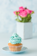 Blue pastel vertical banner with decorated cupcake and bouquet of pink roses in retro shabby chic vase.
