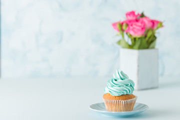 Cupcake with pink decoration and bouquet of pink roses in retro shabby chic vase.