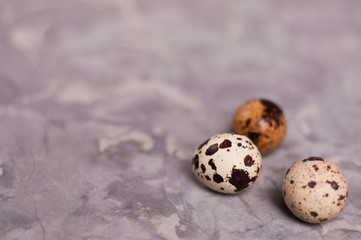 Three spotted fresh quail eggs on old broken worn gray cement floor with copy space