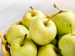 Green ripe apples in a wicker yellow basket