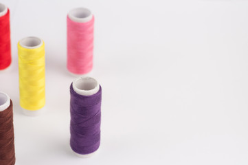 Lot of bobbins of new colorful threads on white background